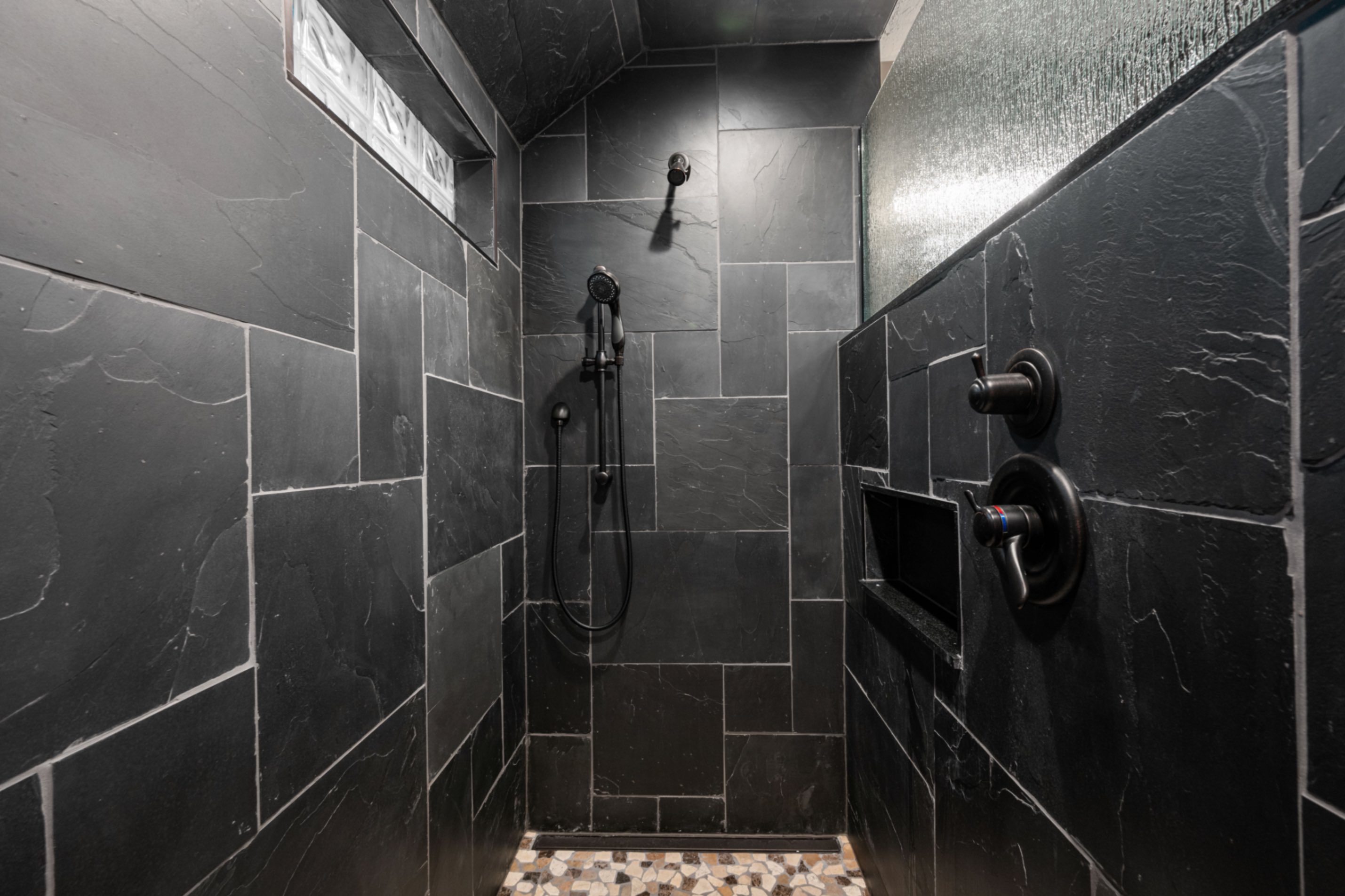 Custom walk-in shower interior with full slate tile and built-in niche