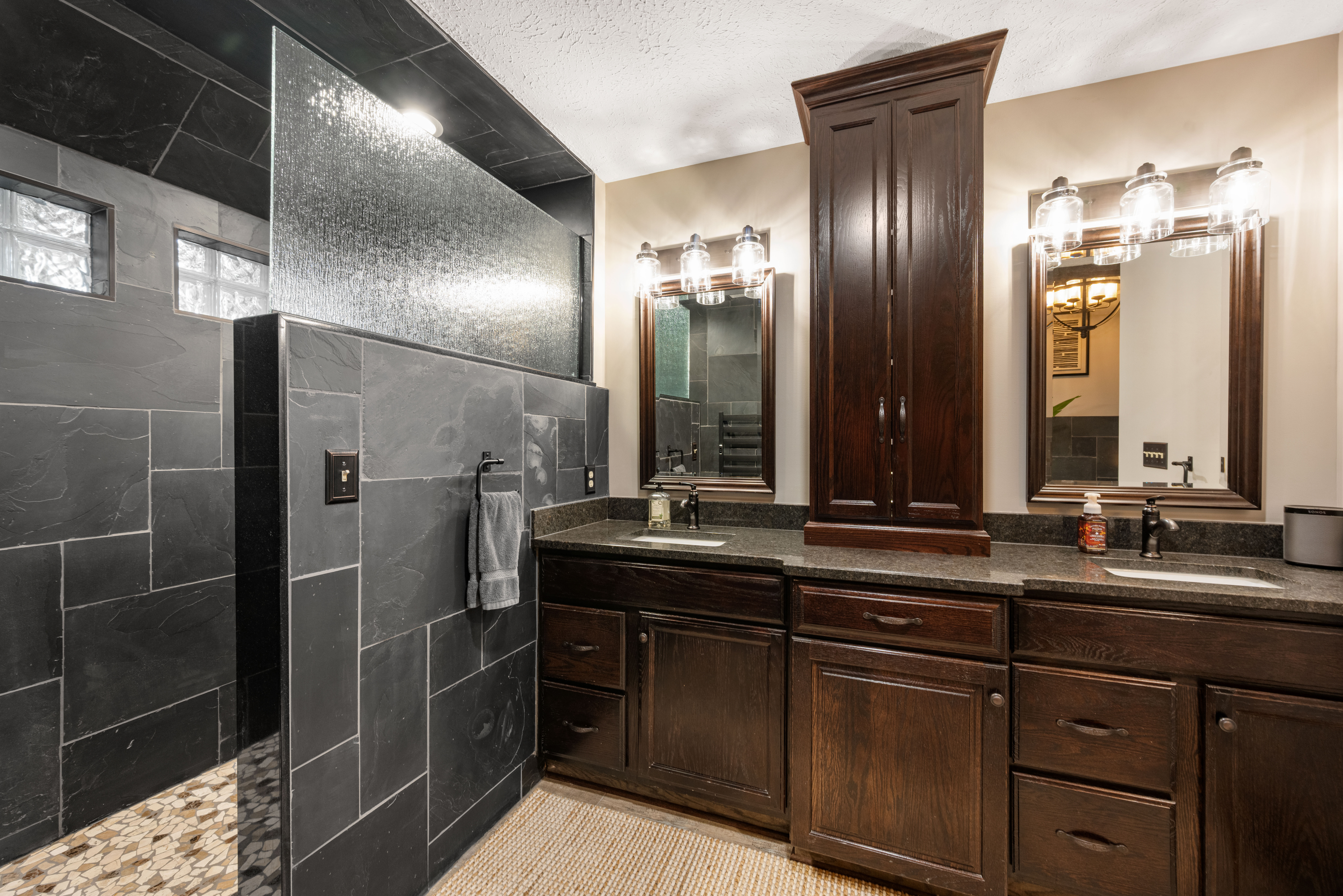 Custom bathroom remodel with dark tile shower and double vanity — Northeast Ohio
